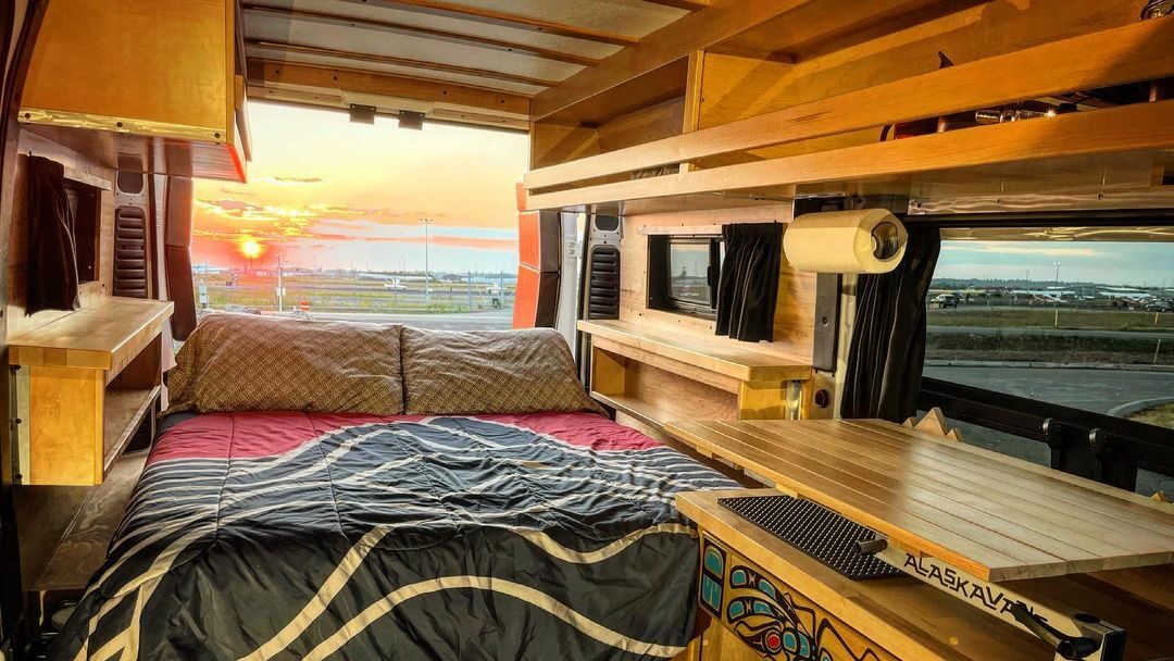 @alaskavans cozy interior of bohemian van camper with a sunset view from the open back door