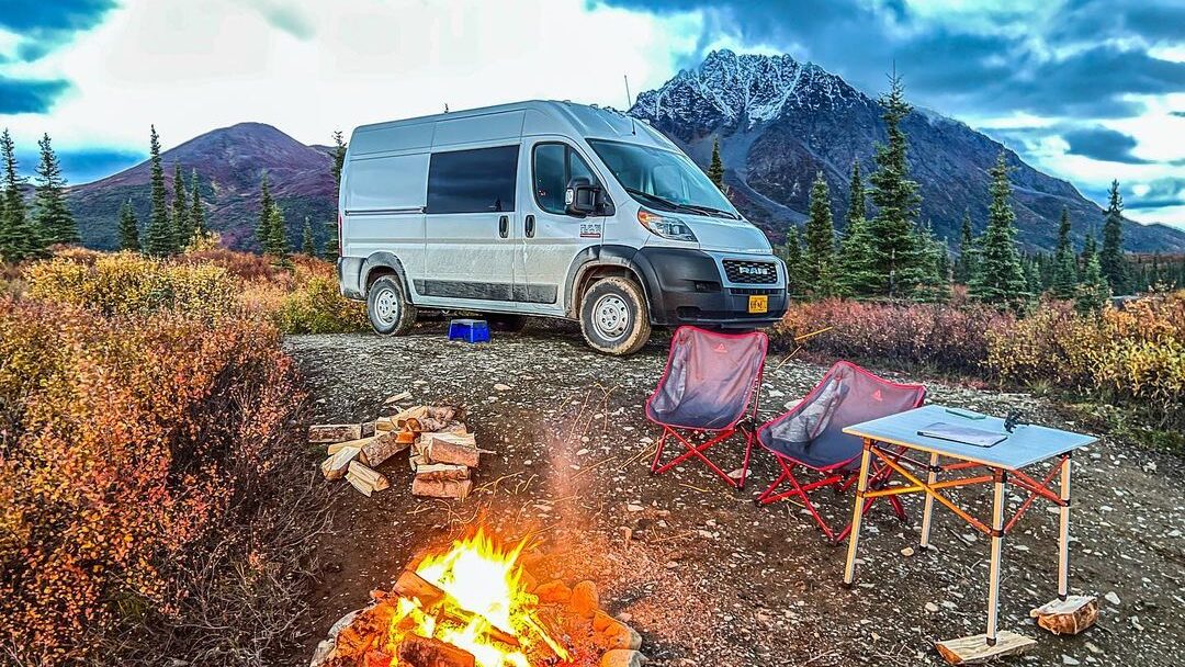 @alpinecampervans rented ram promaster parked near a campfire
