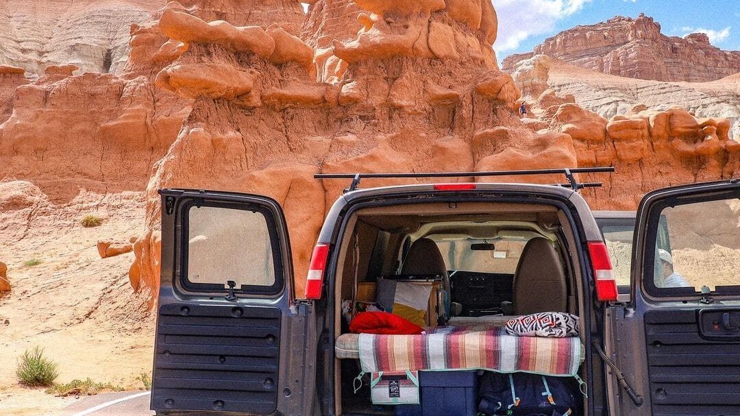 @basecampervans back view of small van with open doors parked in front of red rock formations