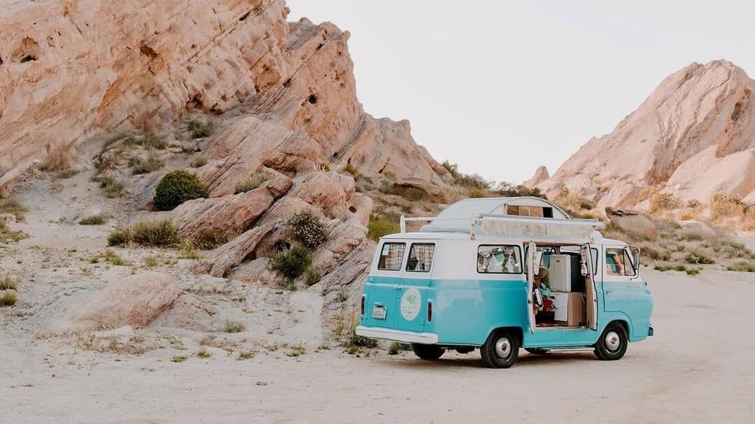 @epochcollective.co vintage white and blue camper van rental parked among large rock formations at Vasquez Rocks Natural Area Park
