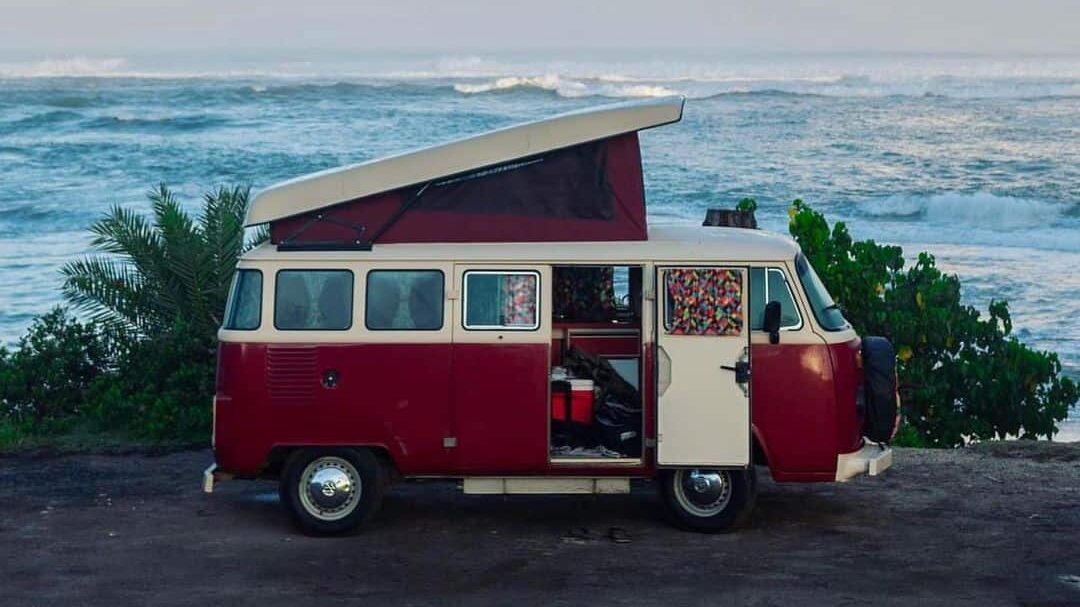 @hisurfcampers red and white VW campervan with pop top parked at the beach