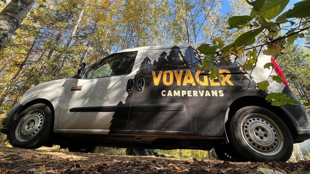 @voyagercampervans Ground-level view of Voyager vanlife van surrounded by trees